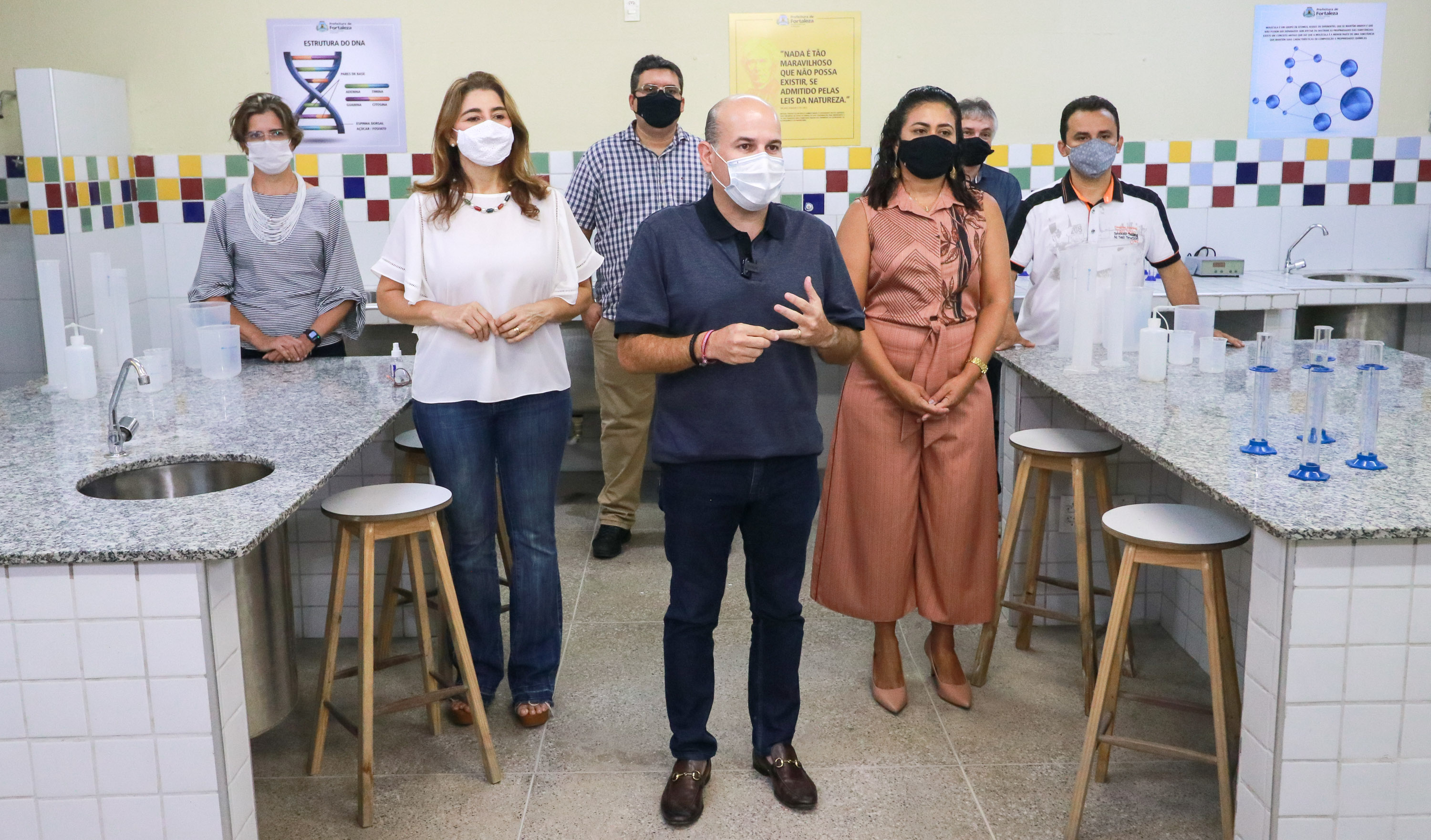 prefeito em pé posando para a foto em laboratório escolar ao lado de pessoas também em pé. todos de máscara